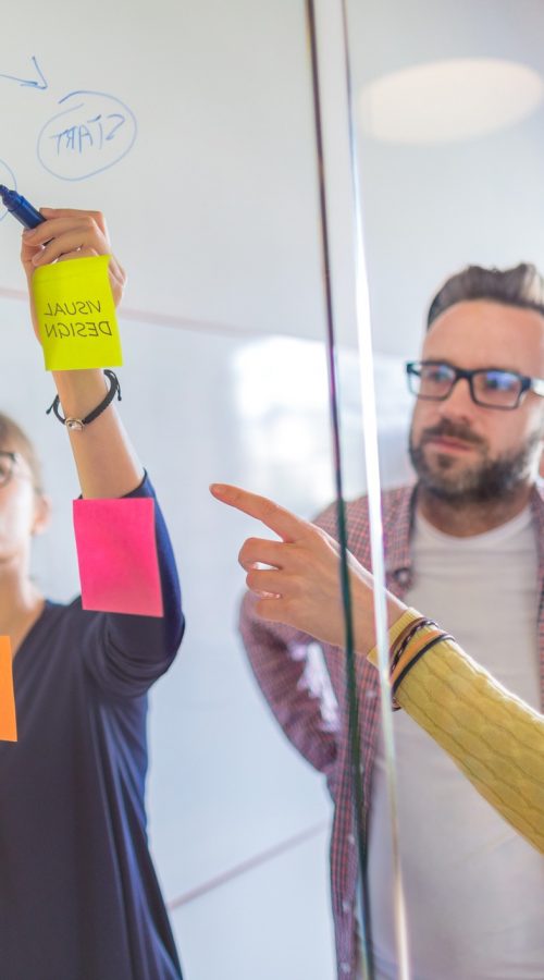 Business people meeting at office and use post it notes to share idea. Brainstorming concept. Sticky note on glass wall.
